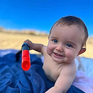 Constance a rejoint le concours — aidez-le/la à gagner de superbes lots ! baby, child, blue_blanket, outdoor, toy, sky, happy, smile, face, arm, hand, skin, blue_eyes, sunlight, daylight, close_up, infant, play, blanket, nature