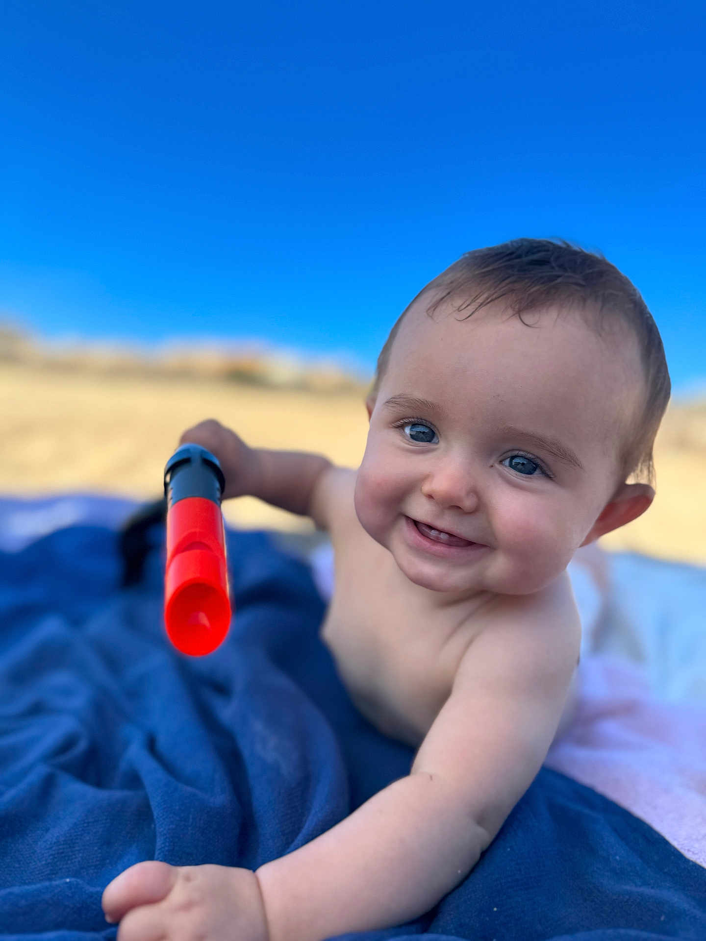 Constance a rejoint le concours — aidez-le/la à gagner de superbes lots ! baby, child, blue_blanket, outdoor, toy, sky, happy, smile, face, arm, hand, skin, blue_eyes, sunlight, daylight, close_up, infant, play, blanket, nature