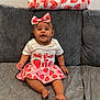 baby, child, smiling, sitting, couch, blanket, headband, bow, strawberry, skirt, shirt, happy, indoor, clothing, cute, portrait, infant, patterned, wall, furniture