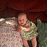 Lainey is registered to the contest to win money with this photo: baby, smiling, infant, dress, couch, pillow, cushion, red, green, patterned, happy, face, skin, legs, hands, indoor, soft_light, cozy, cute, child