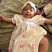 Lainey joined the competition — help win amazing prizes! baby, infant, child, dress, headband, blanket, pink, white, pattern, soft, cute, lying_down, arms_outstretched, legs_outstretched, indoor, comfort, expression, face, person, toddler