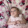 baby, infant, pink_dress, blanket, minnie_mouse, cartoon, pattern, floral, soft_texture, cute, portrait, child, indoor, clothing, person, newborn, sleepwear, toddler, lying_down, decor