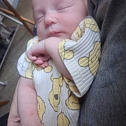 Gracie is registered to the contest to win money with this photo: baby, sleeping, infant, arms, clothing, smiley_face_pattern, person, hand, closeup, soft_lighting, indoor, peaceful, cute, newborn, portrait, cozy, fabric, skin, resting, toddler