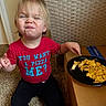 Leo joined the competition — help win amazing prizes! toddler, child, red_shirt, text_on_clothing, scrunched_face, carpet, plate, scrambled_eggs, banana, food, cardboard_box, wicker_chair, indoor, person, casual_clothing, sitting, funny_expression, hand, meal, floor