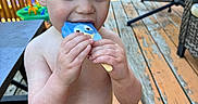 Leo joined the competition — help win amazing prizes! toddler, child, boy, ice_cream, popsicle, blue_popsicle, summer, outdoor, deck, wooden_floor, swim_trunks, lobster_print, bare_chest, toy, furniture, chair, sunlight, happy, snack, playtime