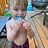 toddler, child, boy, ice_cream, popsicle, blue_popsicle, summer, outdoor, deck, wooden_floor, swim_trunks, lobster_print, bare_chest, toy, furniture, chair, sunlight, happy, snack, playtime