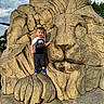 Leo is registered to the contest to win money with this photo: toddler, child, nike, blue_sneakers, stone_sculpture, lion, sculpture, outdoor, park, cloudy_sky, grass, person, statue, rock, young_child, playful, casual_clothing, daylight, nature, fun