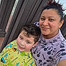 James is registered to the contest to win money with this photo: child, adult, selfie, portrait, smiling, happy, outdoor, backyard, wooden_fence, brick_patio, colorful_clothing, dinosaur_shirt, cartoon_shirt, mickey_mouse, family, mother, son, short_hair, curly_hair, daylight