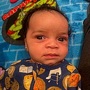 Ayden joined the competition — help win amazing prizes! baby, infant, face, eyes, curly_hair, onesie, clothing, blanket, cartoon, teenage_mutant_ninja_turtles, cookie_pattern, indoor, portrait, child, cute, expression, colorful, soft_toys, resting, young