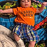Ayden is registered to the contest to win money with this photo: baby, infant, child, orange_shirt, plaid_shorts, socks, blanket, teenage_mutant_ninja_turtles, colorful, cute, lying_down, arms_outstretched, face, eyes, indoor, soft_texture, patterned, fabric, casual_clothing, person