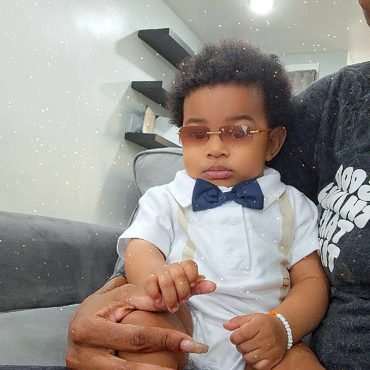 Jonas joined the competition — help win amazing prizes! adult, baby, bow_tie, calm, child, couch, fashion, hand, indoor, light, living_room, manicure, modern_interior, portrait, shelf, sitting, skin, sparkle_filter, sunglasses, white_outfit