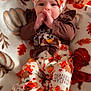 baby, child, thanksgiving, festive_clothing, headband, bow, blanket, autumn, pumpkin, orange, brown, cute, sitting, footwear, indoors, holiday, patterned, cozy, person, portrait