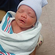 Giovanni joined the competition — help win amazing prizes! newborn, baby, infant, sleeping, swaddled, blanket, hat, striped_clothing, portrait, face, closed_eyes, peaceful, hospital, adult_arm, tattoo, shoes, tile_floor, indoor, caregiver, photograph