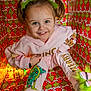 child, girl, smiling, pink_clothing, grinch, headband, pigtails, colorful, patterned_background, holiday_theme, sitting, box, happy, portrait, playful, bright_colors, fun, festive, indoor, footwear