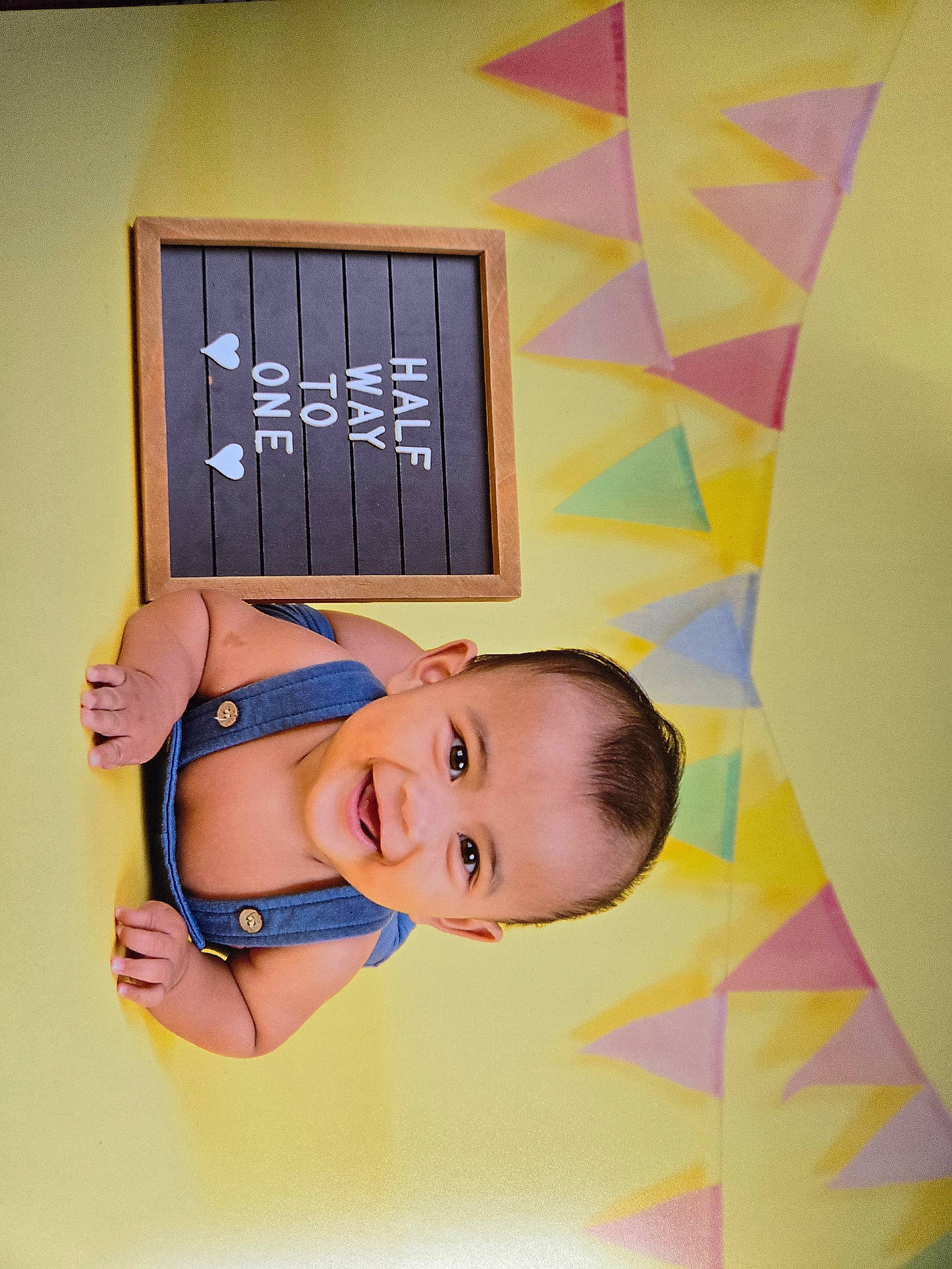 Kris Aivan is registered to the contest to win money with this photo: accessories, baby, blackboard, bodypart, clothing, earring, face, finger, furniture, hand, happy, head, indoors, pants, person, photography, plywood, portrait, smile, wood