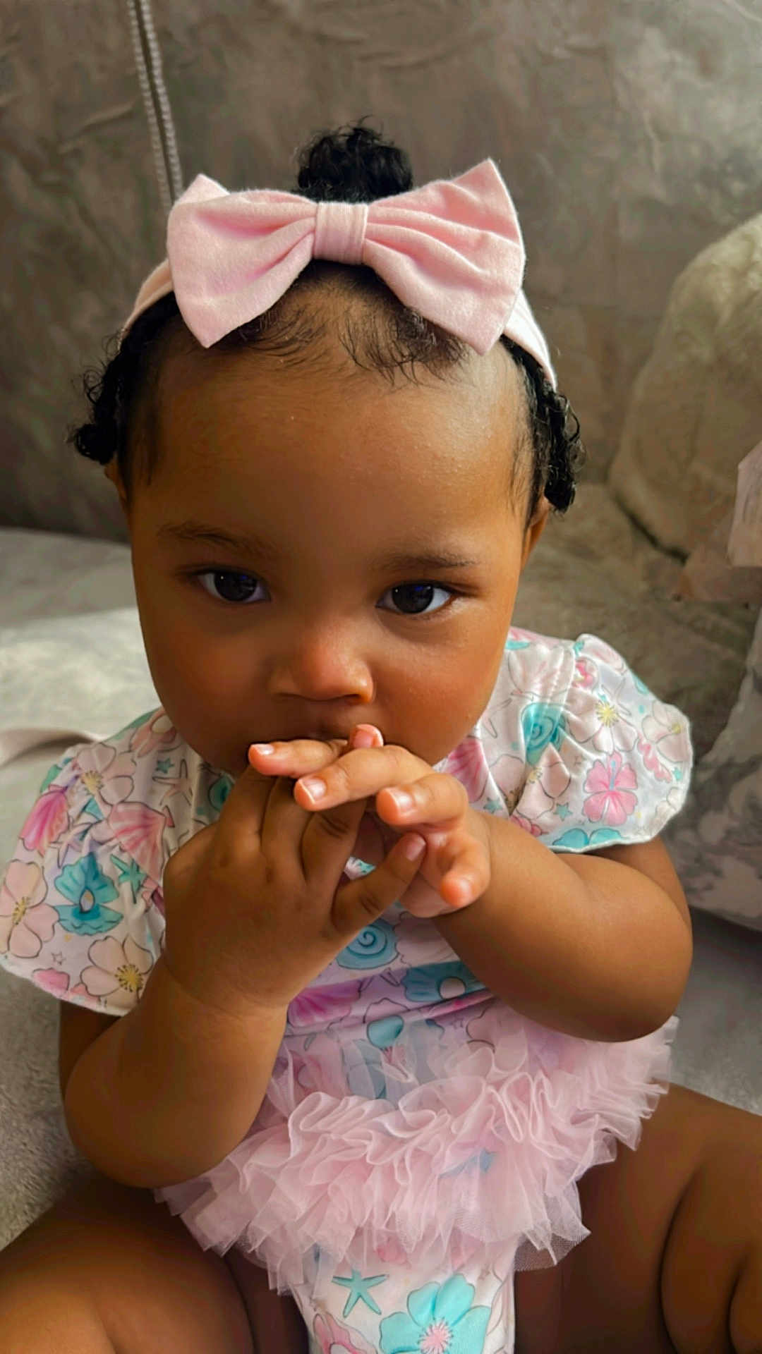 Nature joined the competition — help win amazing prizes! baby, child, girl, pink_bow, floral_dress, ruffles, sitting, cute, portrait, indoors, hand, face, curious, infant, headband, young_child, skin, eyes, fingers, adorable