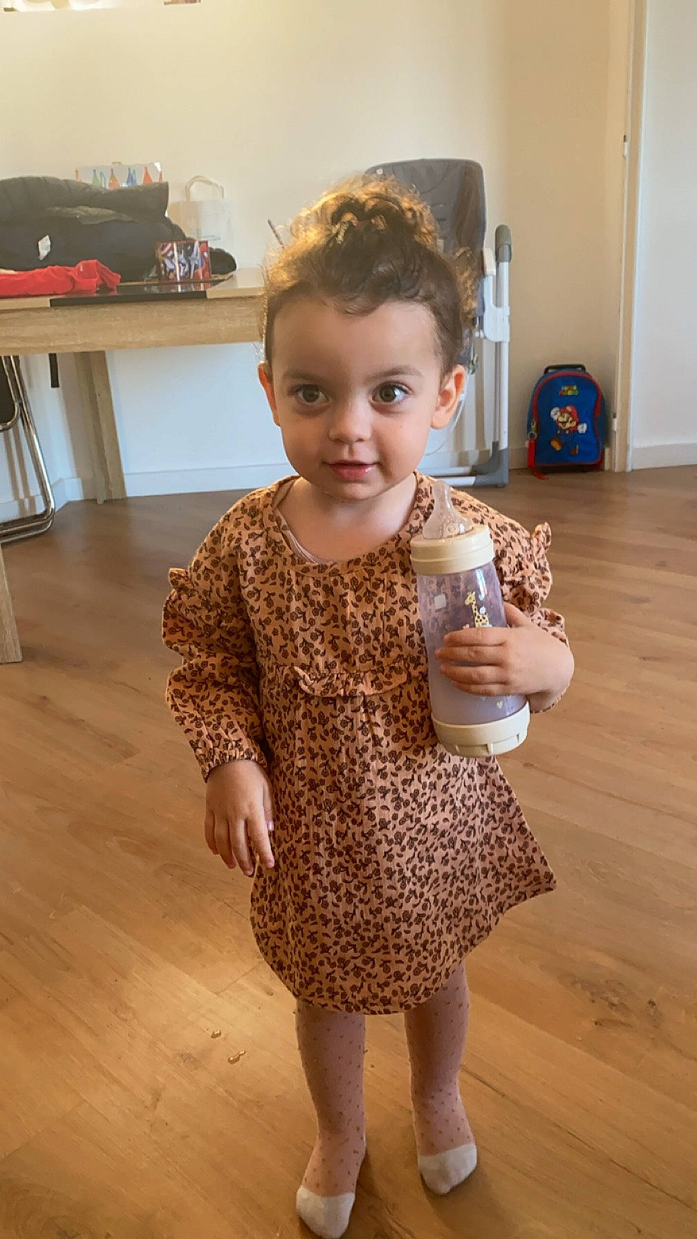 Kataleya a rejoint le concours — aidez-le/la à gagner de superbes lots ! baby_toddler_clothing, blond, child, day_dress, drink, floor, flooring, fun, hardwood, human_leg, joint, one_piece_garment, pattern, person, skin, sleeve, smile, standing, toddler, trunk