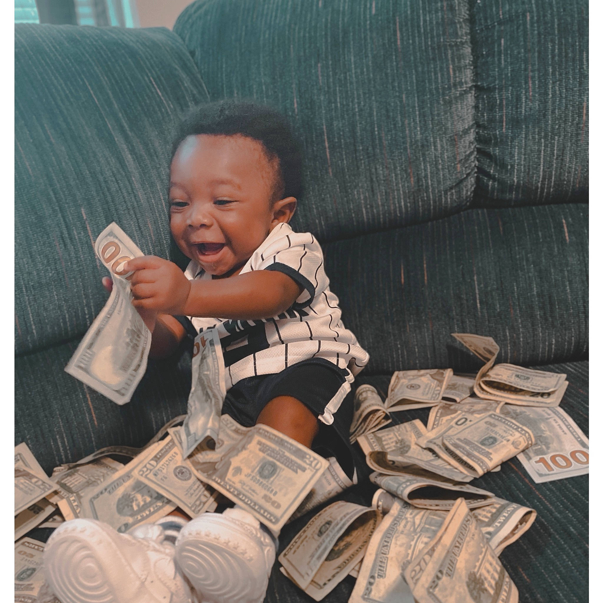 Zakai is registered to the contest to win money with this photo: baby, baby_products, baby_toddler_clothing, bag, banknote, child, comfort, happy, linens, paper, paper_product, pattern, person, room, sitting, sleeve, smile, square, t_shirt, textile