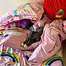 cat, gray_cat, white_paws, blanket, pillow, rainbow, unicorn, pink, bedroom, sleeping, cozy, plush, soft, fabric, cute, resting, indoor, animal, feline, comfort