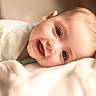 baby, smiling, face, blanket, soft, infant, cute, portrait, lying_down, warm_lighting, happy, child, closeup, skin, expression, indoors, young, cozy, head, eyes