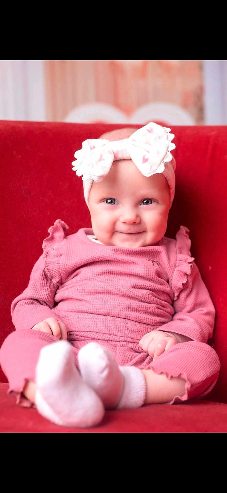Maizie joined the competition — help win amazing prizes! baby, infant, smile, pink_clothing, headband_bow, socks, red_sofa, portrait_photography, chubby_cheeks, ruffled_sleeves, sitting, blue_eyes, cozy, indoor_scene, soft_lighting, adorable, close_up, small_hands, happy, toe_socks