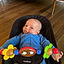 baby, infant, bouncer, blue_onesie, tongue_out, toy, colorful, flower_toy, wooden_floor, babybjorn, indoor, smiling, playful, child, cute, furniture, home, person, seat, happy