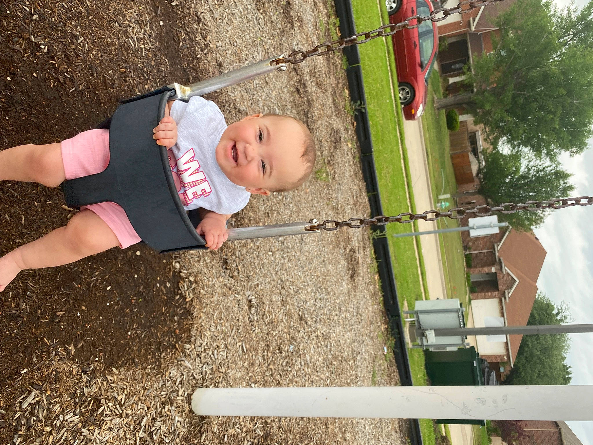 Paisley is registered to the contest to win money with this photo: baby, child, city, fun, grass, house, joy, knee, leisure, outdoor_play_equipment, person, plant, playground, pole, recreation, sky, soil, swing, t_shirt, thigh