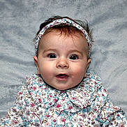 Joséphine a rejoint le concours — aidez-le/la à gagner de superbes lots ! baby, infant, face, headband, floral_clothing, blanket, cute, eyes, portrait, child, smiling, soft_texture, laying_down, young, adorable, person, happy, clothing, closeup, indoors