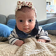 Arya a rejoint le concours — aidez-le/la à gagner de superbes lots ! baby, blanket, blue_cushion, bow, child, cozy, curious, cute, eyes, face, hands, headband, home, indoor, infant, lying_down, person, portrait, soft_texture, striped_clothing