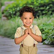 Aries is registered to the contest to win money with this photo: child, boy, smiling, curly_hair, suspenders, short_sleeve_shirt, outdoor, portrait, happy, greenery, pathway, cute, young, fashion, casual, person, nature, background_blur, standing, light