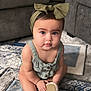 Aaliyah is registered to the contest to win money with this photo: baby, child, headband, bow, sitting, carpet, indoor, fuzzy_slippers, curious, plush_furniture, blue_carpet, gray_couch, cute, portrait, infant, clothing, hands, feet, floor, room