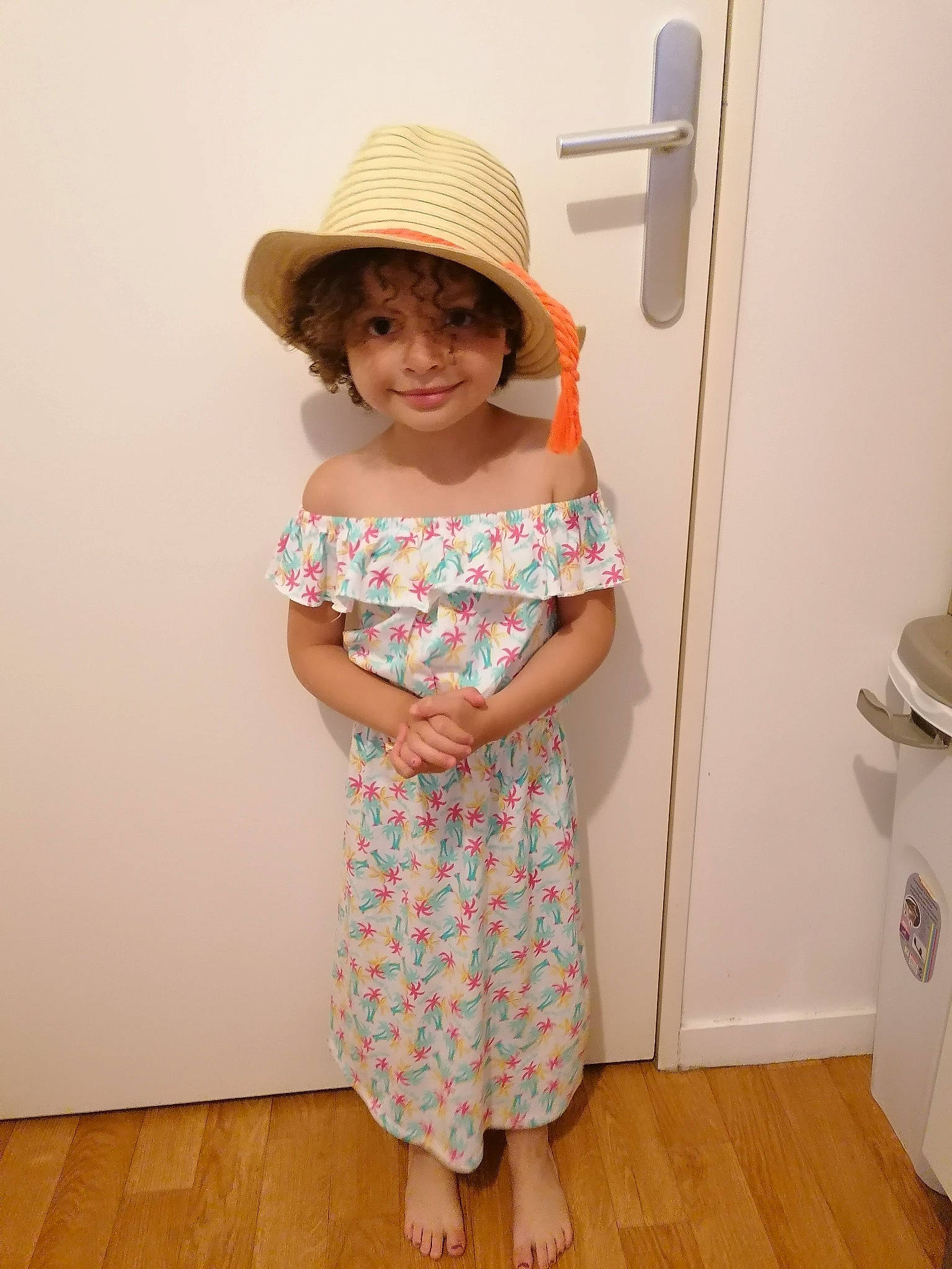 Olivia participe au concours pour gagner de l'argent avec cette photo : clothing, dress, fashion_design, floor, flooring, happy, hardwood, hat, joy, knee, neck, one_piece_garment, person, shoulder, sleeve, smile, sun_hat, toddler, trunk, waist