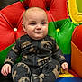 Anthony is registered to the contest to win money with this photo: baby, child, onesie, animal_print, colorful_chair, cushion, happy, smiling, indoor, soft_fabric, seated, cute, infant, portrait, plush, comfort, small_hand, footwear, face, skin