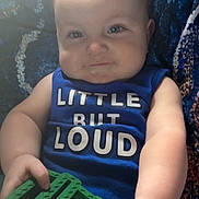 Anthony is registered to the contest to win money with this photo: baby, child, blue_shirt, toy, indoor, sitting, curious, hands, face, patterned_background, soft_light, cute, smile, infant, person, closeup, plush, chubby_cheeks, casual_clothing, holding