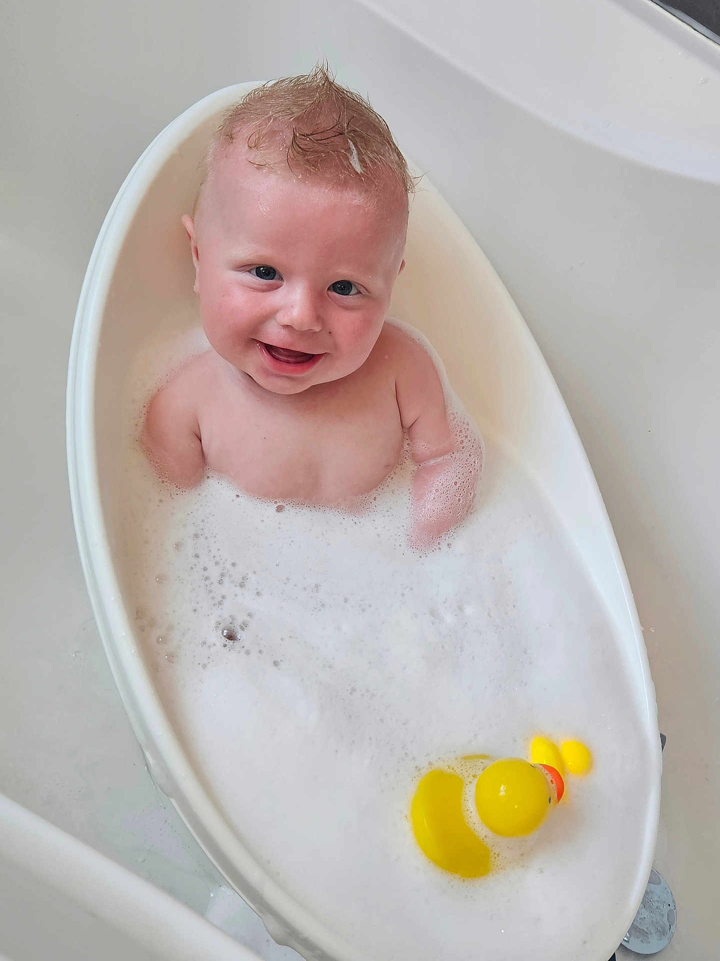 Toby is registered to the contest to win money with this photo: baby, bath, bubble_bath, foam, rubber_duck, smiling, child, bathtub, water, white_tub, cute, moawk_hair, happy, skin, human, infant, playful, wash, clean, splash