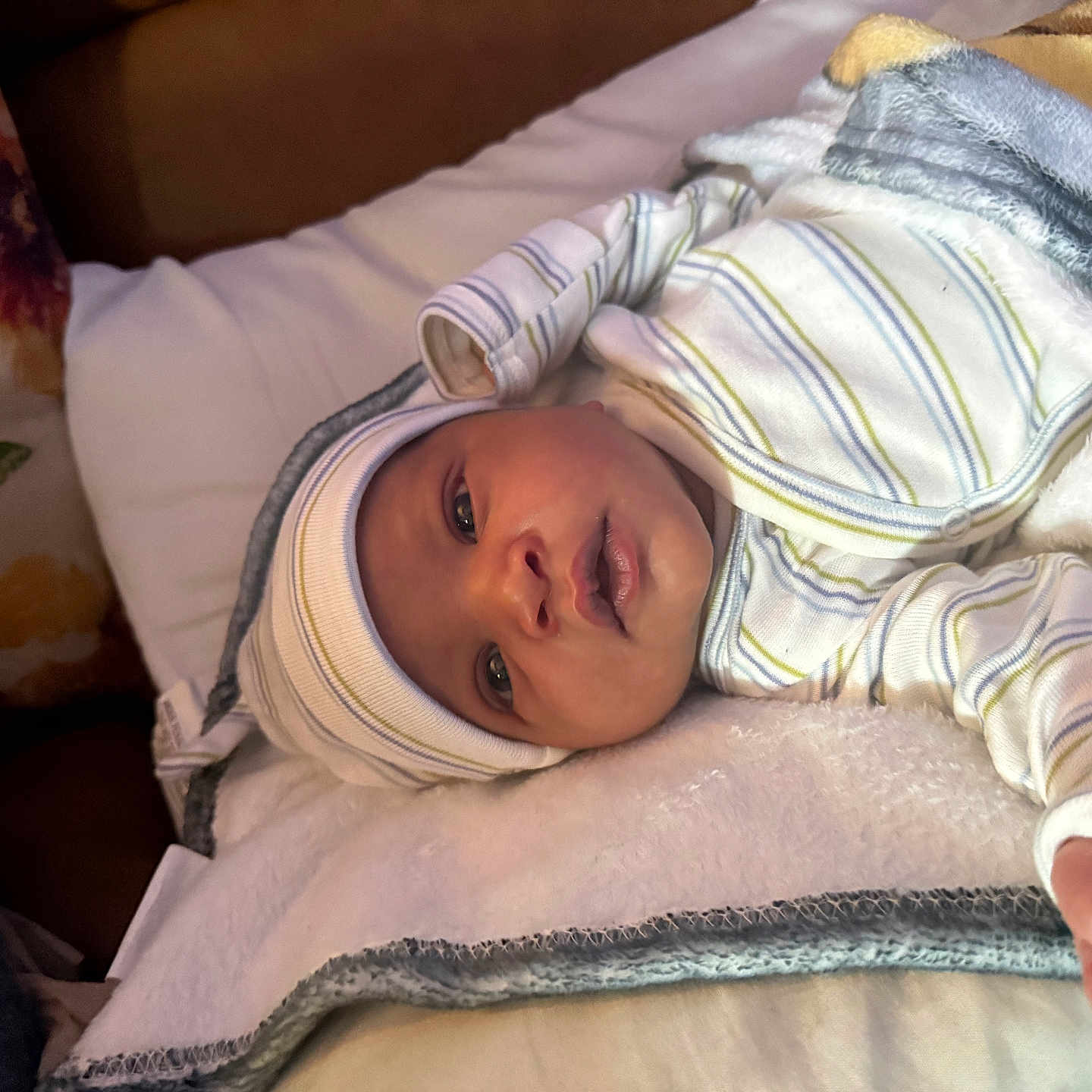 Azriel is registered to the contest to win money with this photo: baby, newborn, infant, blanket, striped_clothing, hat, sleeping, face, hand, soft_texture, pillow, floral_pattern, indoors, resting, cute, portrait, child, cozy, bed, toddler