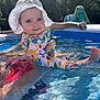 baby, child, water, pool, sunhat, swimsuit, adult_hand, smile, outdoor, summer, sunlight, reflection, water_surface, nature, trees, blue, colorful_clothing, cute, person, recreation