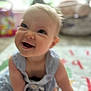 Finnley is registered to the contest to win money with this photo: baby, smiling, child, infant, play_mat, blue_dress, indoors, cute, happy, face, skin, person, sitting, young_child, blurry_background, light, expression, adorable, closeup, portrait