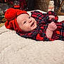 Léna participe au concours pour gagner de l'argent avec cette photo : baby, smiling, red_hat, plaid_clothing, blanket, indoor, holiday_decor, nutcracker, toy_train, wood_floor, portrait, infant, cute, happy, cozy, festive, child, face, lying_down, warm_lighting