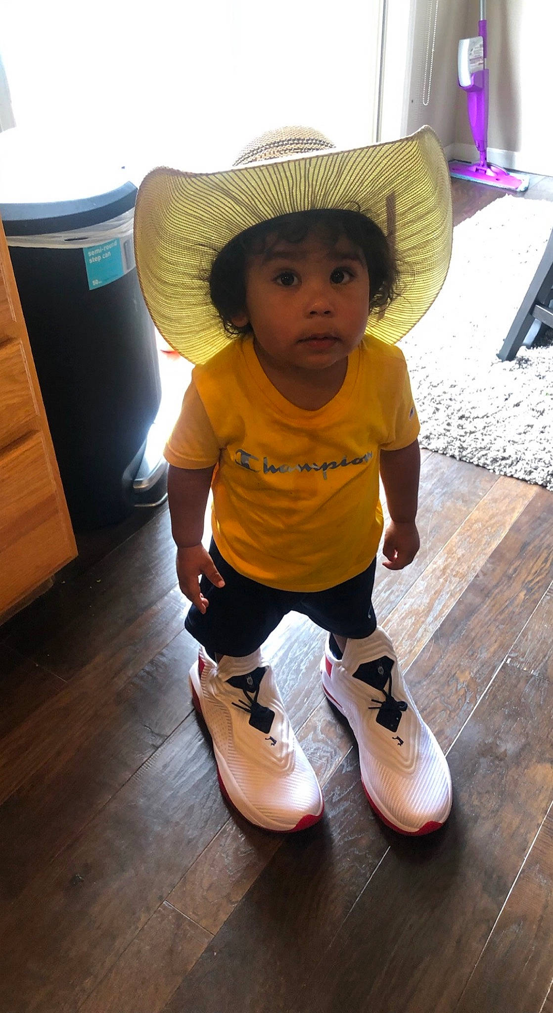 Chevéyo is registered to the contest to win money with this photo: baby, baby_toddler_clothing, cap, cheek, child, face, floor, flooring, fun, happy, hardwood, hat, human_leg, knee, outdoor_shoe, person, standing, sun_hat, toddler, white