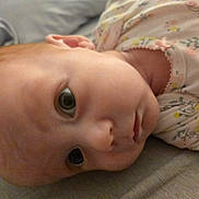 Luna is registered to the contest to win money with this photo: baby, infant, face, eyes, clothing, onesie, pattern, floral, skin, head, laying, portrait, closeup, cute, child, newborn, soft, expression, indoors, resting