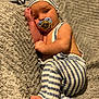 baby, infant, pacifier, striped_clothing, striped_hat, blanket, soft_texture, barefoot, sleepwear, cute, resting, indoors, child, portrait, young_child, toddler, cozy, relaxed, comfort, lying_down