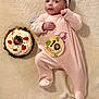 baby, infant, onesie, headband, blanket, cake, cherry, chocolate, celebration, milestone, wooden_sign, lion, cute, sleepwear, lying_down, soft_texture, food, dessert, portrait, indoors