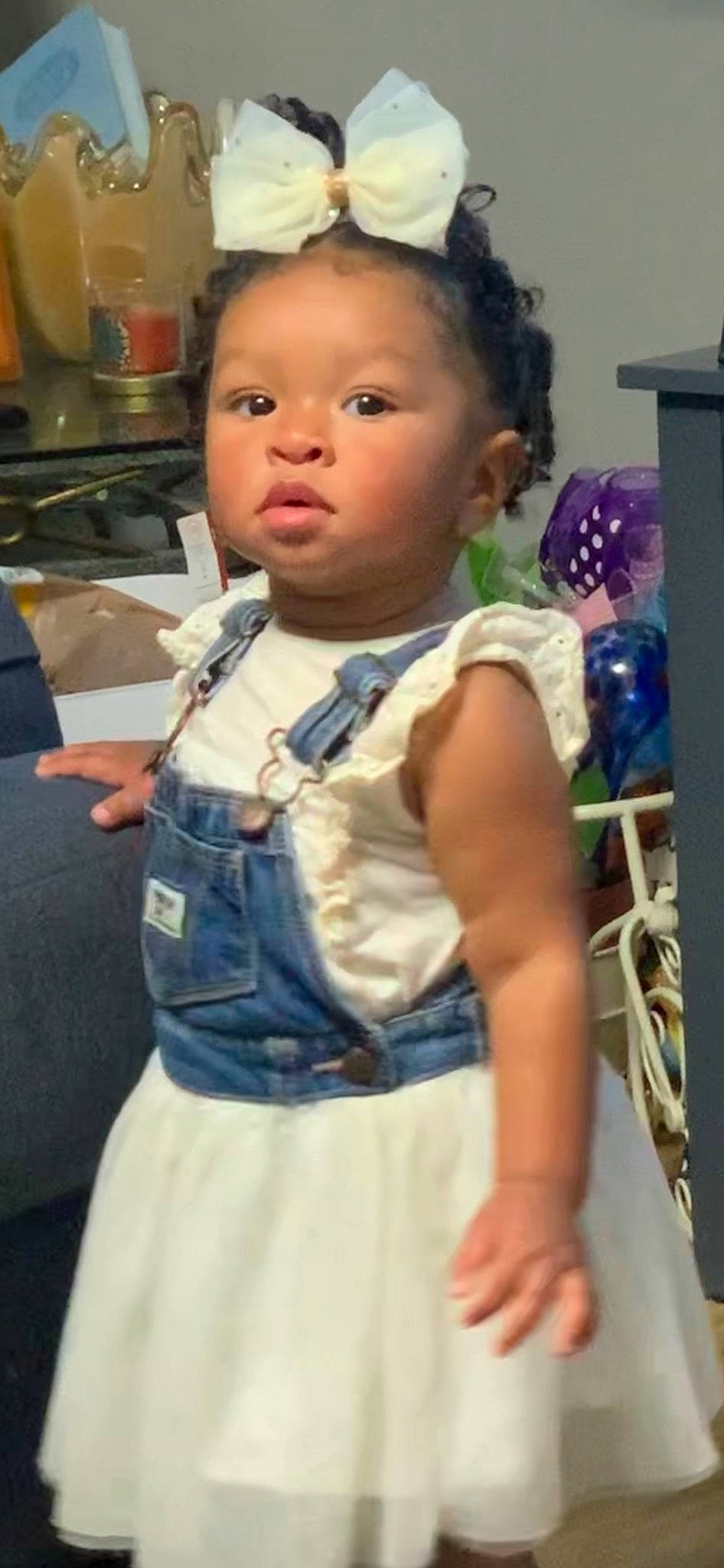 Novah is registered to the contest to win money with this photo: baby, baby_toddler_clothing, cheek, child, day_dress, denim, dress, electric_blue, eye, happy, pattern, person, room, ruffle, sitting, skin, sleeve, t_shirt, toddler, toy