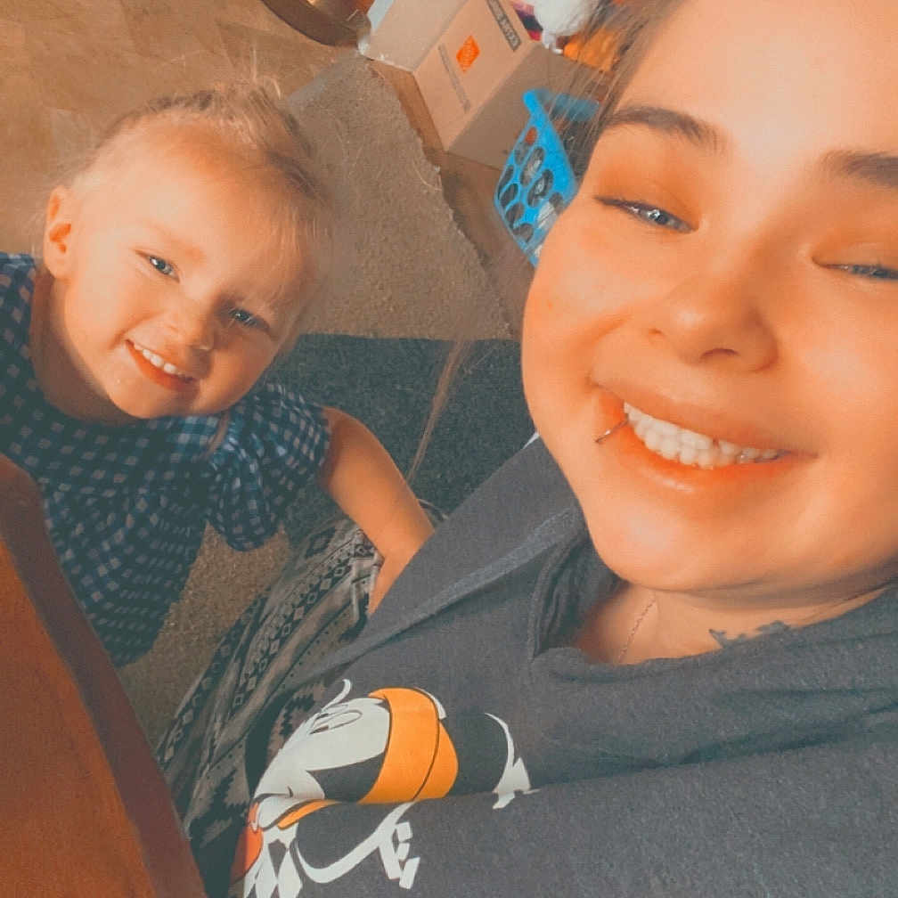 Bailey is registered to the contest to win money with this photo: adult, baby, bodypart, clothing, couch, face, female, furniture, happy, head, laughing, mouth, person, photography, portrait, selfie, smile, t_shirt, teeth, woman