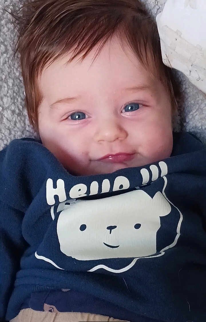 Noé participe au concours pour gagner de l'argent avec cette photo : baby, blue_eyes, smile, face, infant, shirt, clothing, graphic, bear, text, hello, lying_down, soft_texture, cute, child, portrait, young, person, cozy, casual