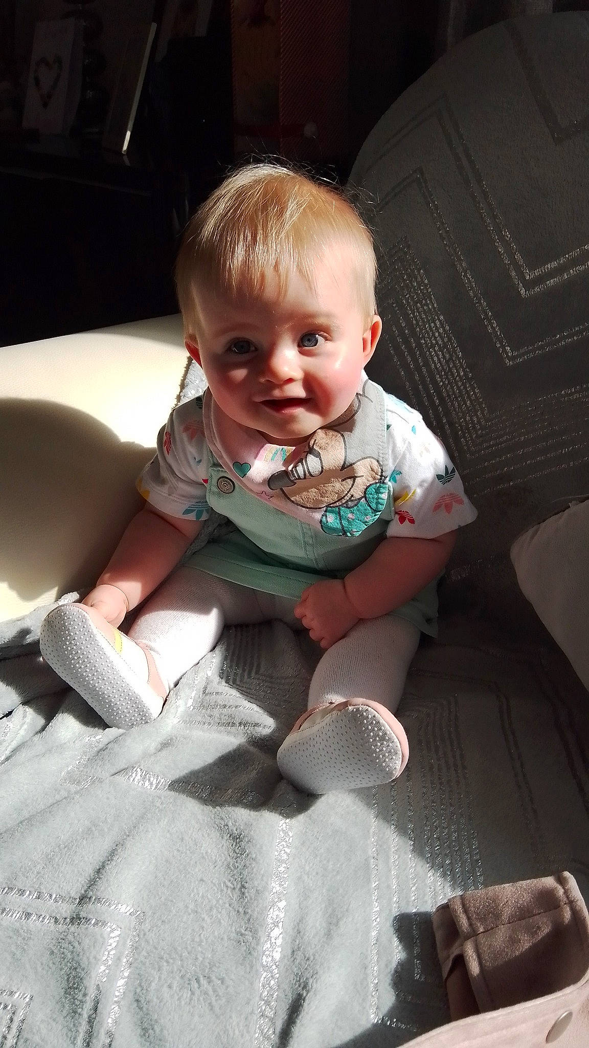 Addison is registered to the contest to win money with this photo: baby, baby_products, baby_toddler_clothing, cheek, child, comfort, couch, flash_photography, floor, flooring, fun, happy, human_leg, linens, mouth, person, room, sitting, smile, sock