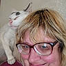 cat, person, glasses, shoulder, blonde_hair, white_cat, indoor, close_up, portrait, pet, feline, happy, smiling, casual, relaxed, friendly, companion, cute, face, human