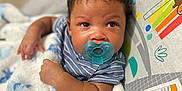 Messiah is registered to the contest to win money with this photo: baby, pacifier, blanket, infant, child, blue, striped_clothing, cute, face, skin, hair, seat, colorful, animal_illustration, warning_label, soft, resting, indoors, closeup, portrait