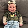 baby, smiling, couch, headband, bow, camouflage, shirt, pants, infant, happy, child, clothing, portrait, indoor, person, young, cute, comfortable, seated, joyful